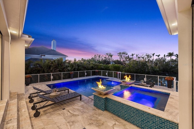 pool at dusk with a patio area, an outdoor fire pit, an in ground hot tub, and pool water feature