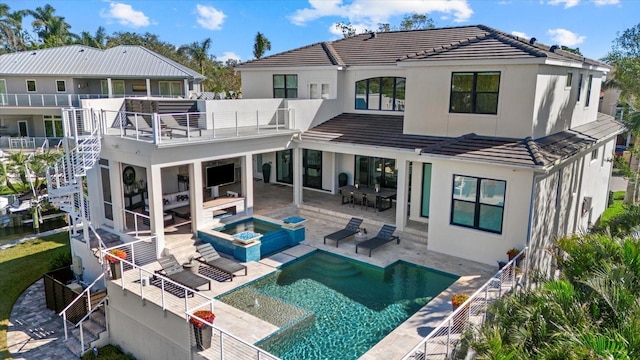 rear view of house featuring a pool with hot tub, a balcony, and a patio area