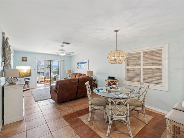 tiled dining area featuring ceiling fan with notable chandelier