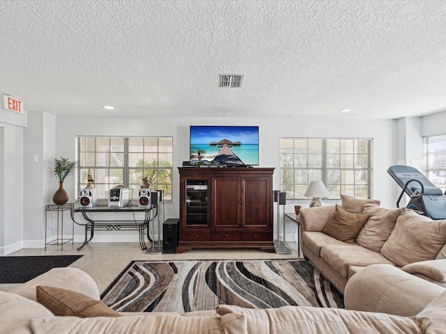 living room with a textured ceiling, recessed lighting, speckled floor, visible vents, and baseboards