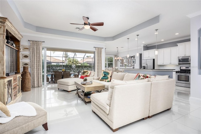 living room featuring a tray ceiling, crown molding, a wealth of natural light, and ceiling fan