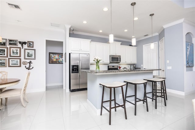 kitchen featuring white cabinetry, a center island with sink, dark stone counters, and appliances with stainless steel finishes