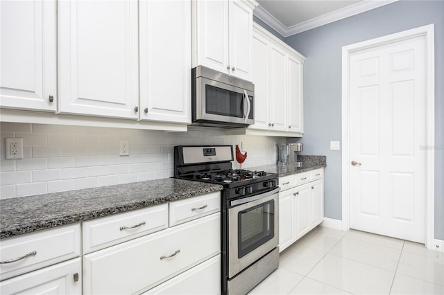 kitchen with white cabinetry, ornamental molding, appliances with stainless steel finishes, dark stone counters, and decorative backsplash