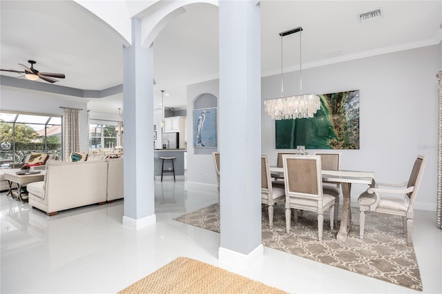 dining space with crown molding, ceiling fan with notable chandelier, and ornate columns