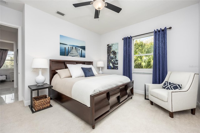 bedroom with ceiling fan, multiple windows, and light carpet