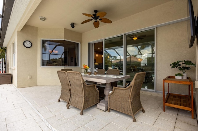 view of patio featuring ceiling fan and glass enclosure