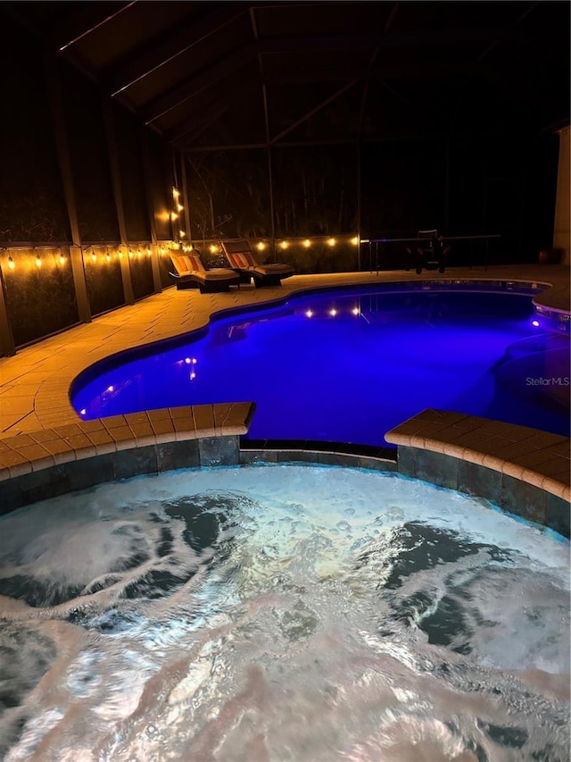 view of pool featuring an in ground hot tub and glass enclosure