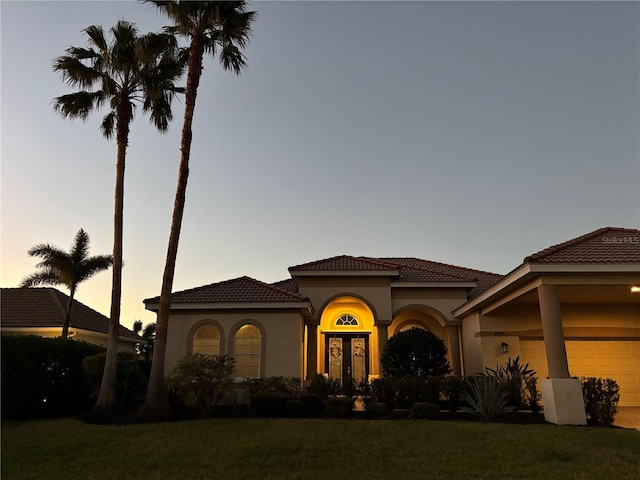 mediterranean / spanish-style house with a yard, a garage, and french doors