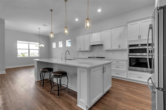 kitchen featuring white cabinetry, appliances with stainless steel finishes, an island with sink, and custom exhaust hood