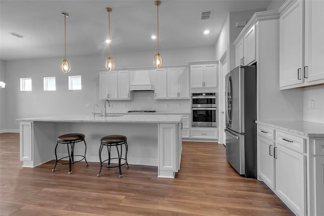 kitchen featuring premium range hood, stainless steel appliances, decorative light fixtures, and white cabinets