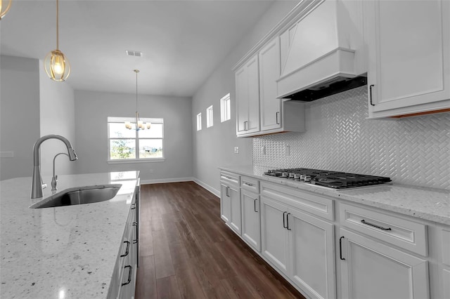 kitchen featuring sink, light stone countertops, custom range hood, white cabinets, and stainless steel gas stovetop