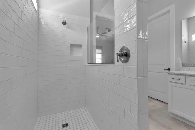 bathroom with tiled shower and vanity