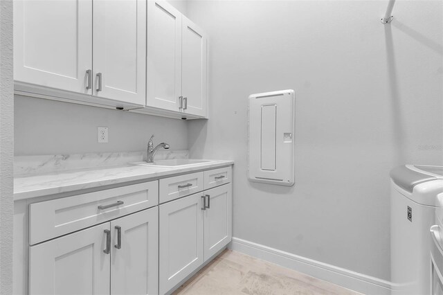 clothes washing area with cabinets, sink, and washing machine and clothes dryer