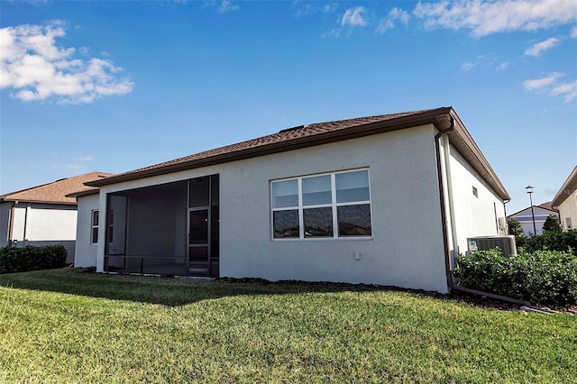 rear view of house featuring cooling unit and a lawn