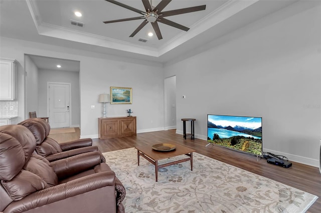 living room with crown molding, ceiling fan, a raised ceiling, and hardwood / wood-style floors