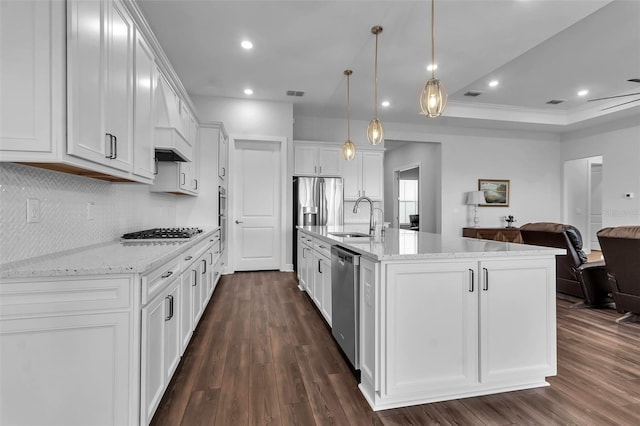 kitchen featuring stainless steel appliances, an island with sink, pendant lighting, and white cabinets