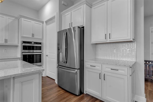 kitchen with dark hardwood / wood-style floors, tasteful backsplash, white cabinetry, stainless steel appliances, and light stone countertops