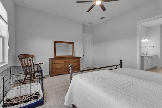 bedroom featuring light colored carpet, ceiling fan, and ensuite bathroom