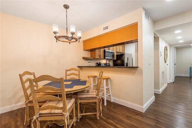 dining room with dark hardwood / wood-style floors and an inviting chandelier