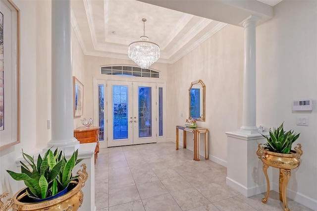 foyer entrance featuring an inviting chandelier, a tray ceiling, ornamental molding, and ornate columns