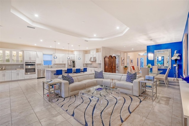 living room with light tile patterned floors and a raised ceiling