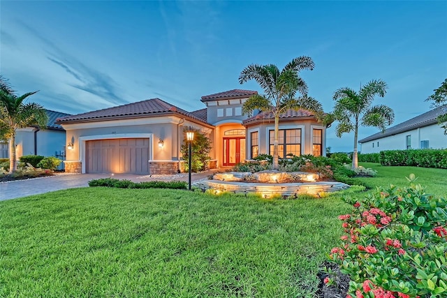 mediterranean / spanish home featuring a garage and a lawn