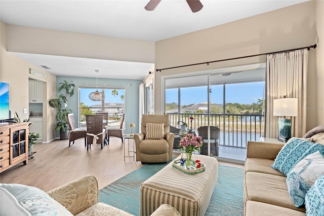 living room with a water view, ceiling fan, and light wood-type flooring