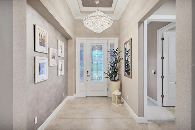 tiled entryway with a raised ceiling, crown molding, and an inviting chandelier