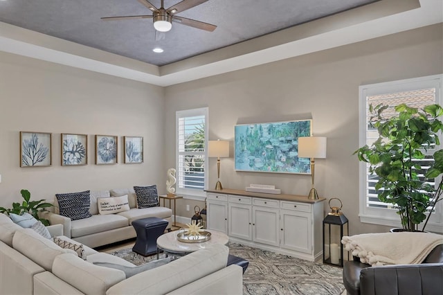 living room featuring a tray ceiling and ceiling fan