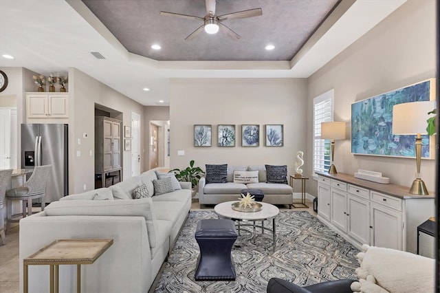 living room with ceiling fan and a raised ceiling