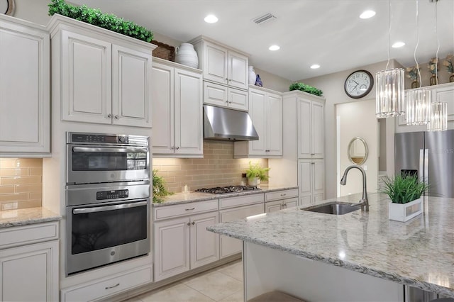 kitchen with light tile patterned flooring, sink, hanging light fixtures, stainless steel appliances, and white cabinets