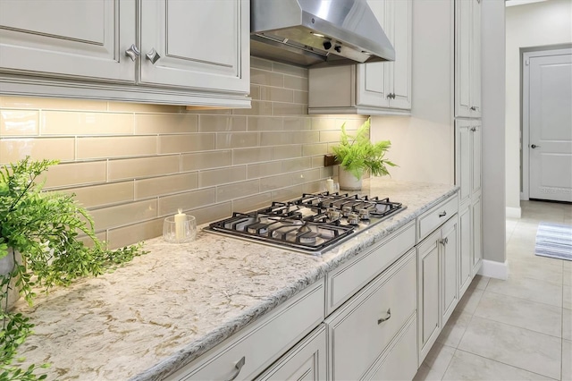 kitchen with tasteful backsplash, stainless steel gas cooktop, light tile patterned floors, and white cabinets