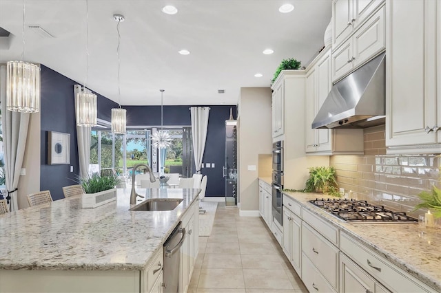 kitchen featuring sink, light stone countertops, stainless steel gas stovetop, and a center island with sink