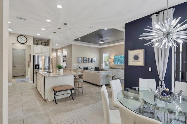 kitchen with a center island with sink, hanging light fixtures, a kitchen breakfast bar, light tile patterned floors, and sink