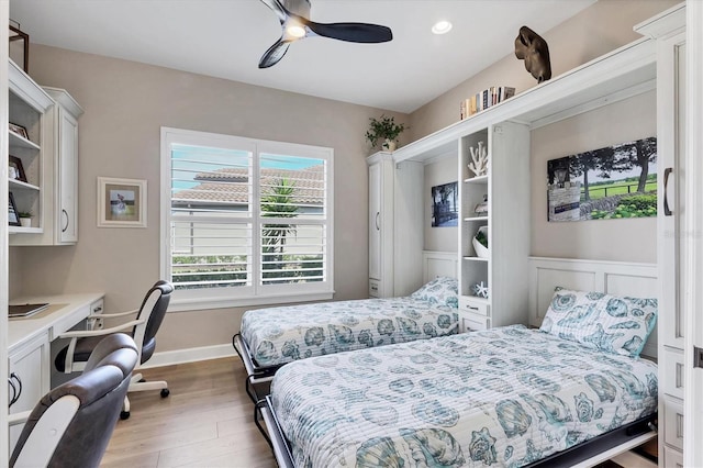 bedroom with ceiling fan, built in desk, and hardwood / wood-style floors