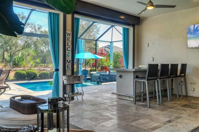 interior space featuring ceiling fan, exterior bar, and glass enclosure