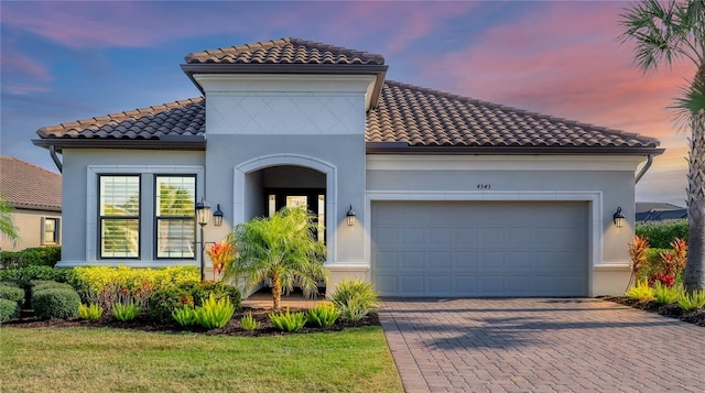 mediterranean / spanish house featuring a garage and a lawn