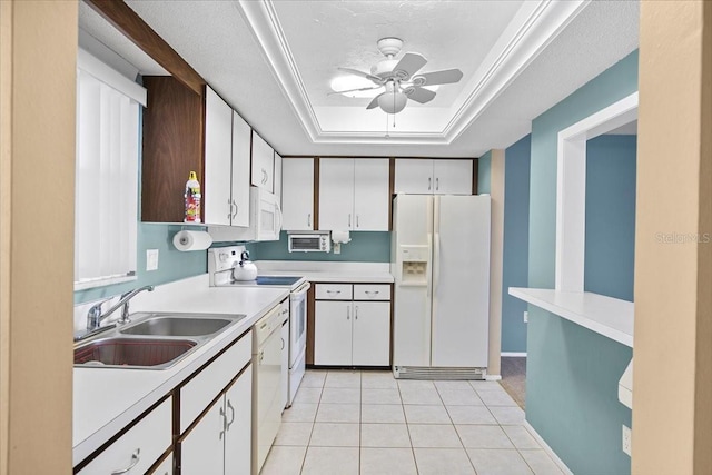 kitchen featuring white appliances, a tray ceiling, light countertops, white cabinetry, and a sink