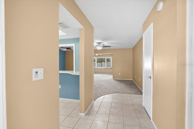 hall featuring visible vents, baseboards, and light tile patterned floors