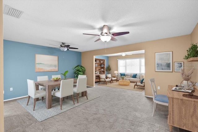 dining room featuring a textured ceiling, carpet, visible vents, and baseboards