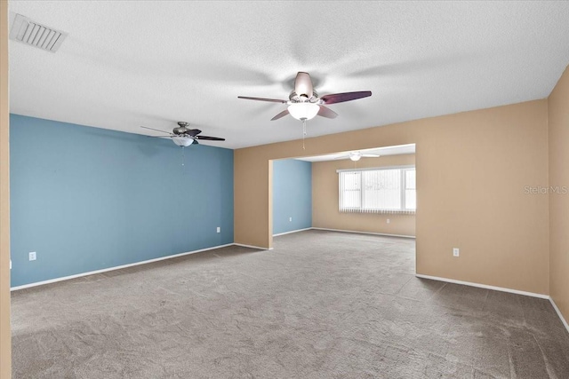 spare room with light colored carpet, visible vents, a textured ceiling, and baseboards