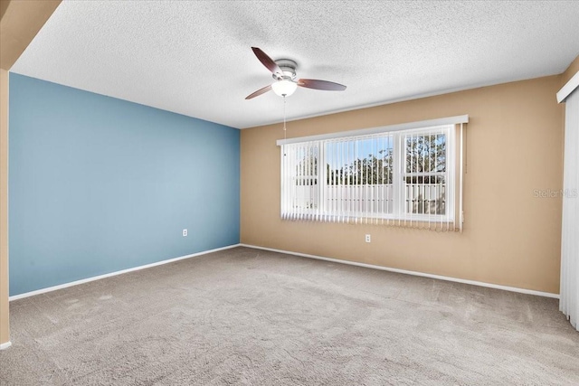 spare room featuring baseboards, a textured ceiling, a ceiling fan, and light colored carpet