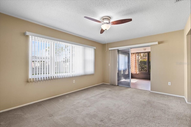 unfurnished room with a textured ceiling, carpet floors, a ceiling fan, and baseboards