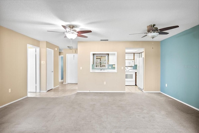 spare room with a ceiling fan, visible vents, light carpet, and a textured ceiling