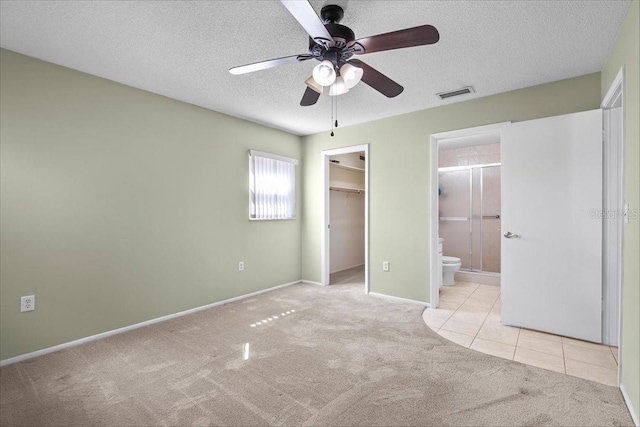 unfurnished bedroom featuring a textured ceiling, light carpet, visible vents, a spacious closet, and a closet