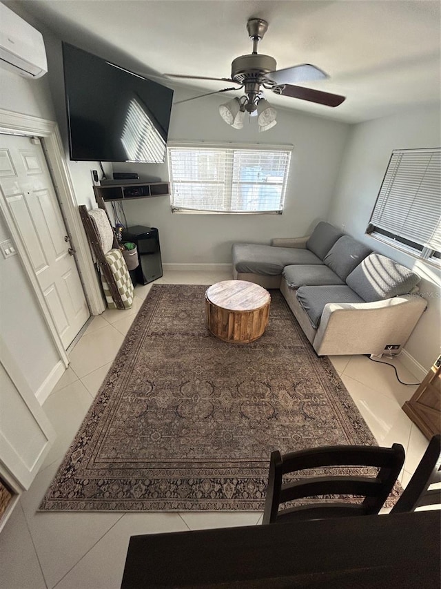 living room featuring light tile patterned floors, a wall unit AC, and ceiling fan