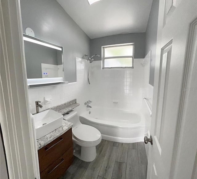 full bathroom featuring hardwood / wood-style flooring, shower / bath combination, tile walls, vanity, and toilet