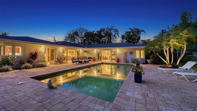 pool at dusk with an outdoor hangout area and a patio area