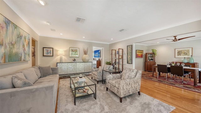 living room with crown molding, ceiling fan, and light hardwood / wood-style flooring