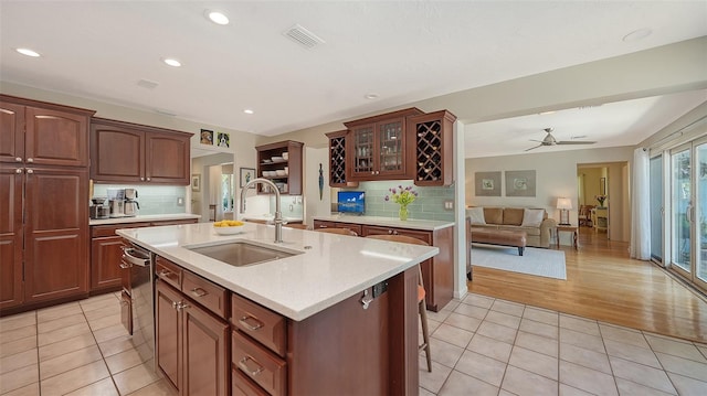 kitchen with sink, a center island with sink, a breakfast bar, and light tile patterned floors